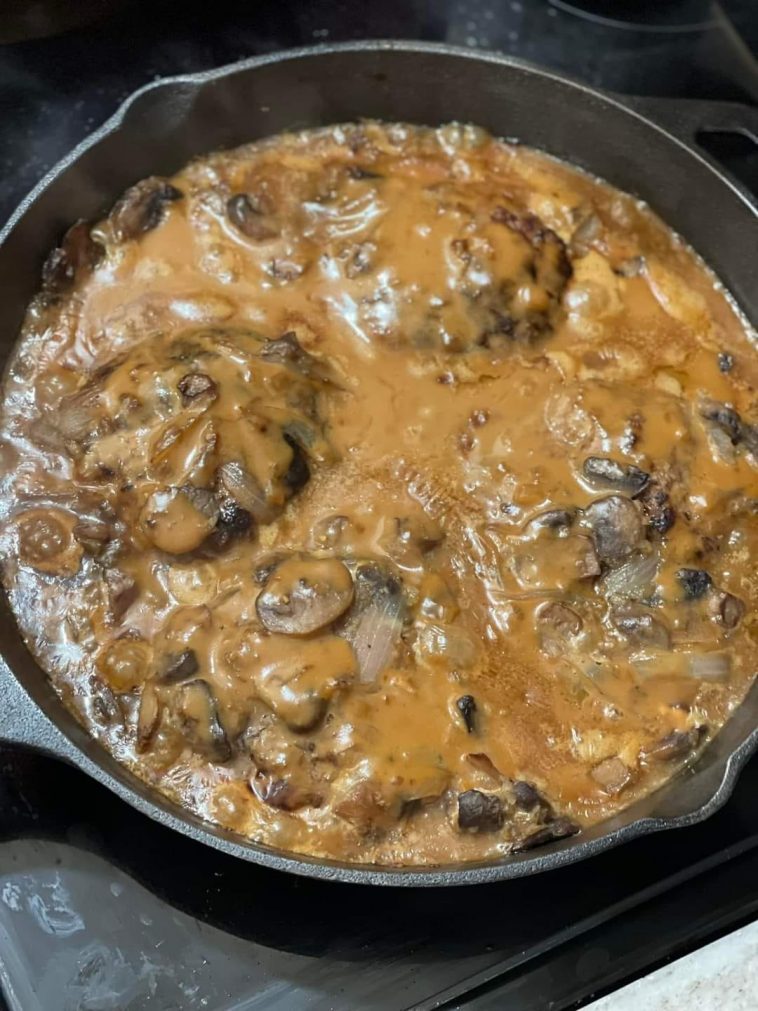 Hamburger steak smothered in brown gravy with mushrooms and onions